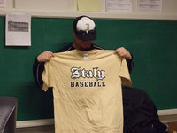 Image: Coach Ward — Coach Ward holds up the t-shirt being sold by the baseball program. The price is $12.00.