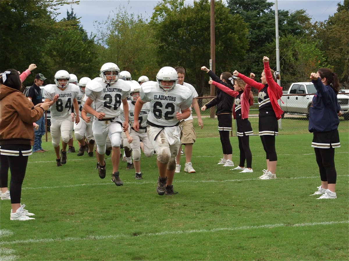 Image: Here they come! — Kevin Roldan(62), Cody Medrano(28) and Chase McGinnis(84) lead the Italy JH Gladiators into battle against the Dawson Bulldogs Thursday.