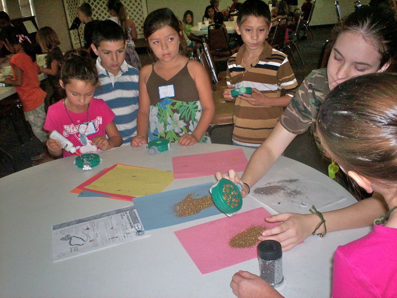 Image: Melissa Smithey — IHS student Melissa Smithey has this young group of Bible Soldiers at full attention as she helps them with glittering their canteens.