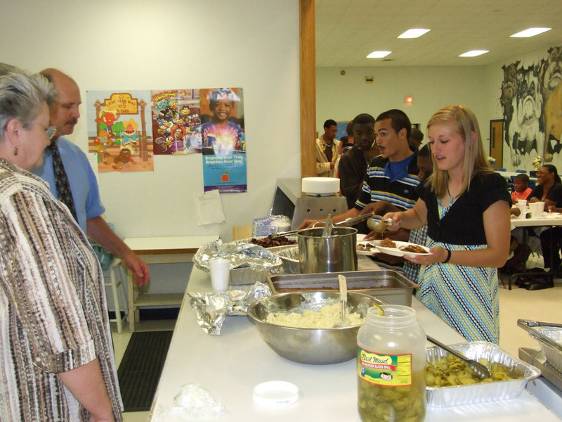 Image: Let’s eat! — Principal Marilee Byrne and Superintendent Don Clingenpeel help serve brisket and sausage to get the banquet cooking.