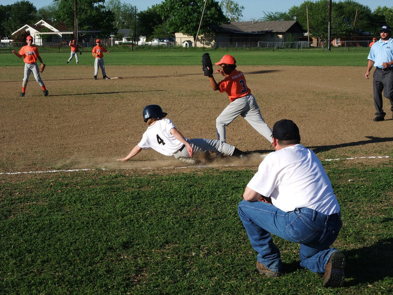 Image: Dust storm — Hillsboro’s throw beats the slide into first base.