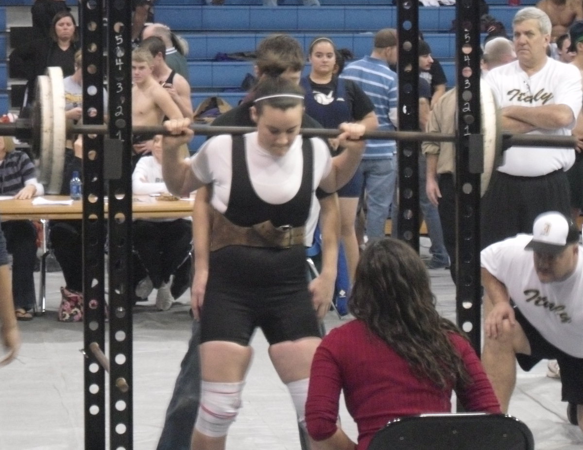 Image: Kaytlyn Bales — Pushing herself to the max is powerlifter Kaytlyn Bales who competes in the squat as Italy coaches watch intently.