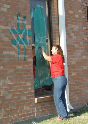 Image: 
    	! — Mrs. Margie Davis puts the finishing touches on a congratulatory banner.  She beams, “I love the band!.”
    