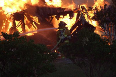 Image: Water conquers fire — Members of the Italy Volunteer Fire Department hose down the burning debris.