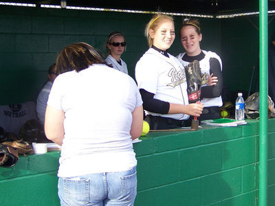 Image: Preparing the book — Manager Blanca Figueroa gets the book ready for the game as Megan and Bailey pose for the camera