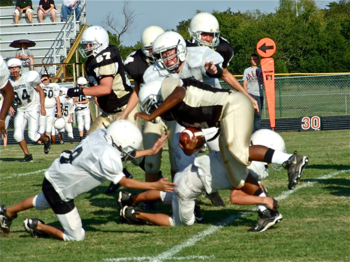 Image: Group tackle — Several of Italy’s Junior High players combine to bring down the Jaguar back.