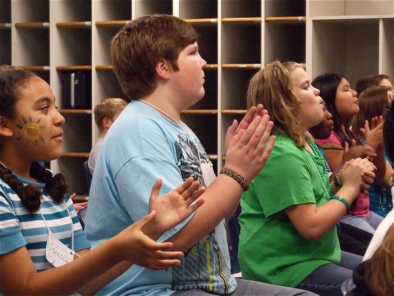 Image: The beat goes on — The 6th grade band works on both clapping rhythms while pretending to blow air thru an instrument.