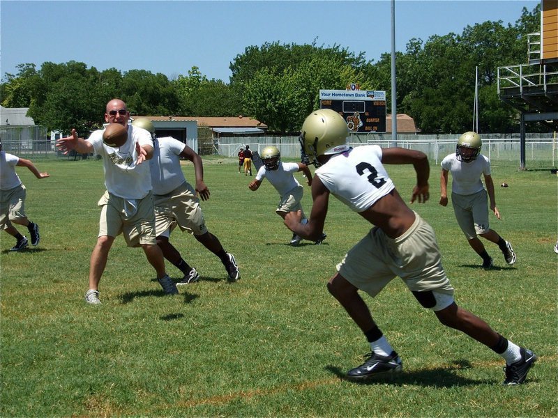 Image: New defensive coach, new 2A classification, same old gold tradition — Italy’s new defensive coordinator Jeff Richters pitches to senior Heath Clemons(2) who will test the Gladiator defense’s pursuit effort. Photo by: Barry Byers