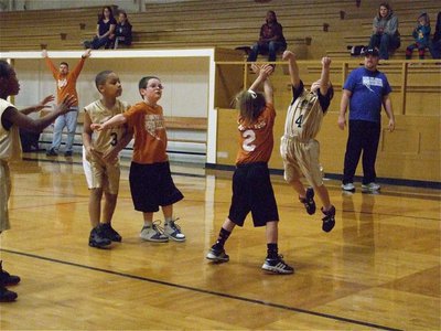 Image: Bryce gets air — Bryce DeBorde(4) jumps high to get up a shot while Cornelius Jones(3) and Zorian Burley(12) try to get open.