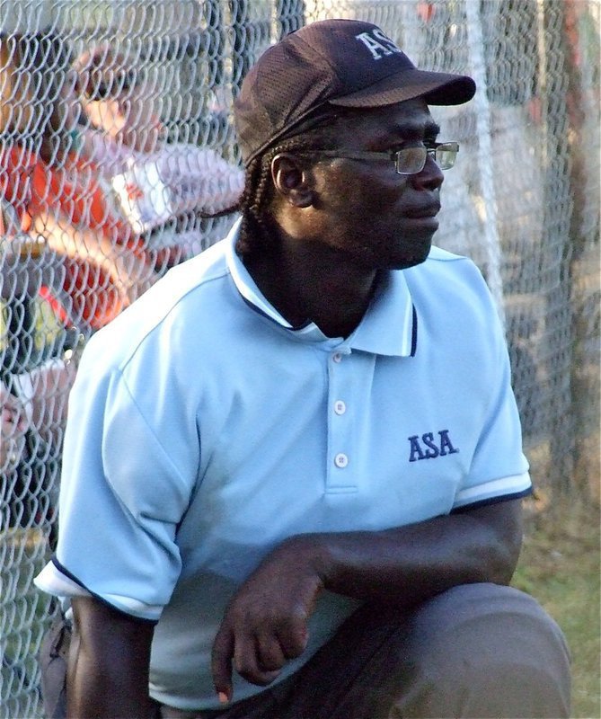 Image: Blue takes a breather — Hillsboro’s ASA Umpire Sammy Cauley takes a knee during a break in the action.