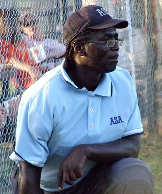Image: Blue takes a breather — Hillsboro’s ASA Umpire Sammy Cauley takes a knee during a break in the action.