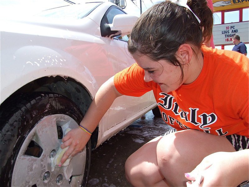 Image: Clean as a whistle — Bailey DeBorde diligently scrubs the tires.