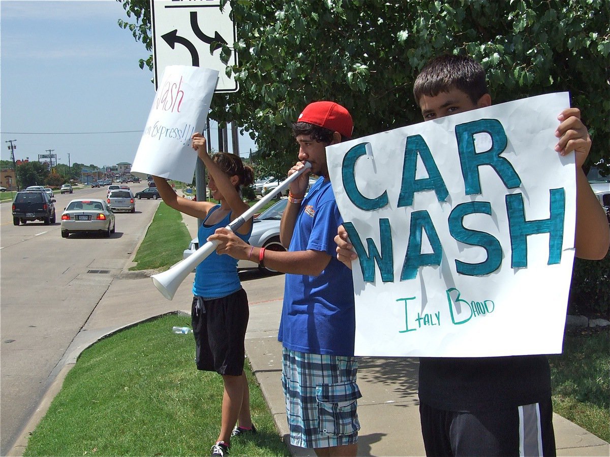Image: Eat more chicken! — Jennifer Hernandez and Reid Jacinto hold the signs and Michael Martinez toots his own horn, all in an effort to attract customers to the Chicken Express Restaurant.