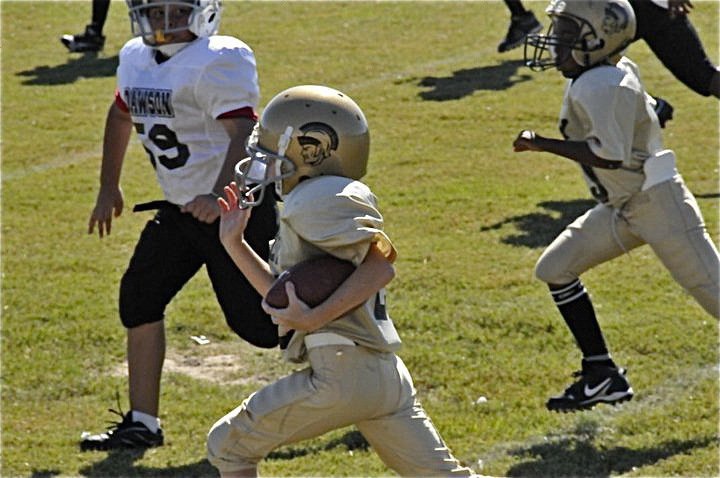Image: Garrett gashes defense — Garrett Cash(28) breaks tackles down Italy’s sideline for a big gain against Dawson. Cash also scored on an extra point conversion run for the IYAA Minors team.