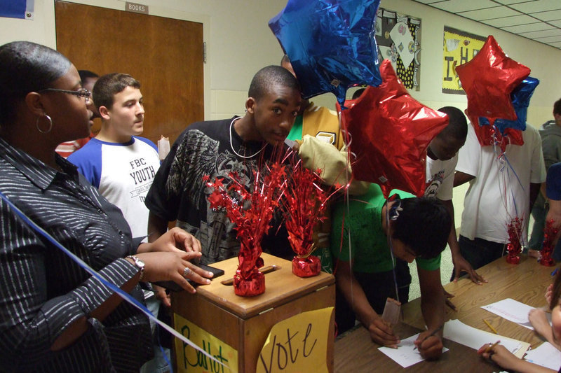 Image: Jasmine Wallace helps — The lines formed to the right as each student waited to cast their ballot for their favorite candidate. Each voter was stamped to keep the election clear.
