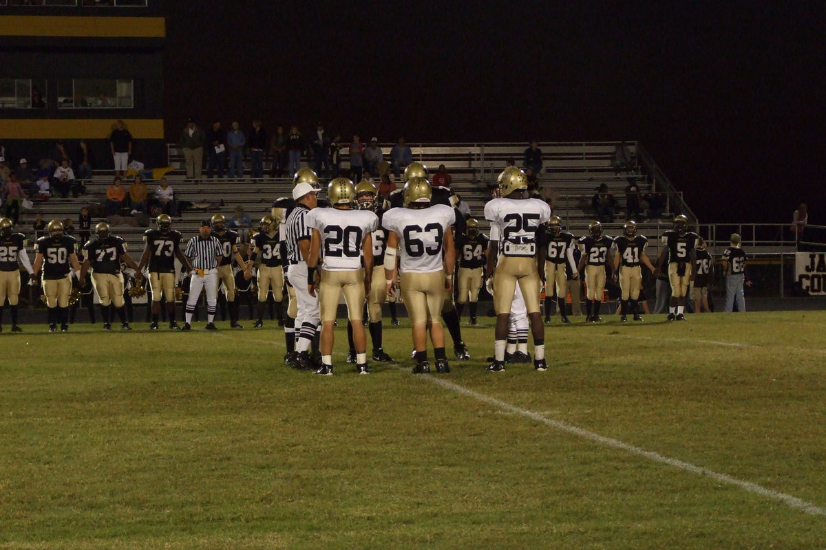 Image: Captains meet in middle — #20-Clay Major, #63-Zach Hernandez and #25-Diamond Rogers listen to the referees.