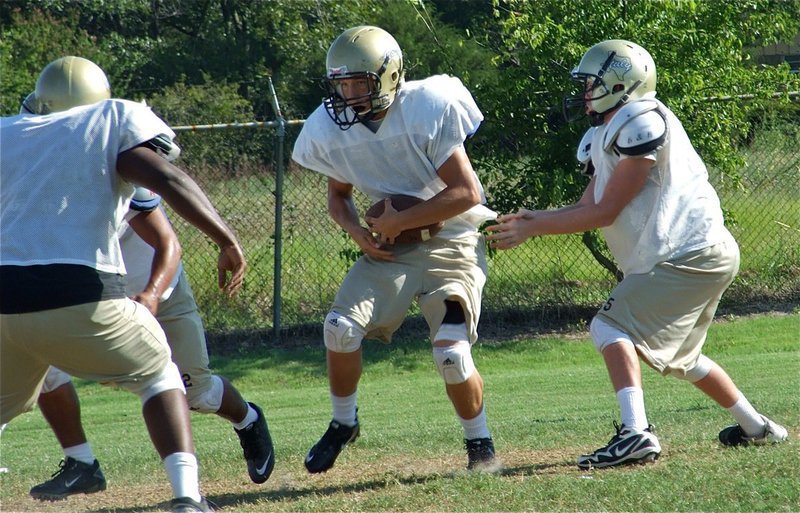 Image: It’s all yours — Justin Buchanan hands off to Kyle Jackson during Wednesday’s practice.