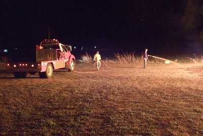 Image: Italy Fire Department — Sal Perales and Tommy Sutherland spray the area down around the bonfire.