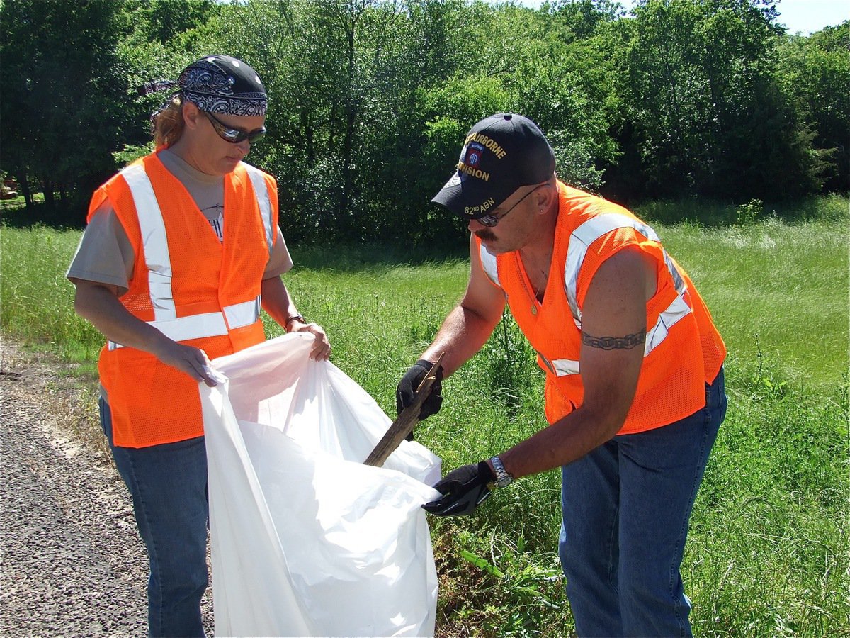 Image: Trash teamwork — Cheryl holds the bag and Barry fills it up with debris.