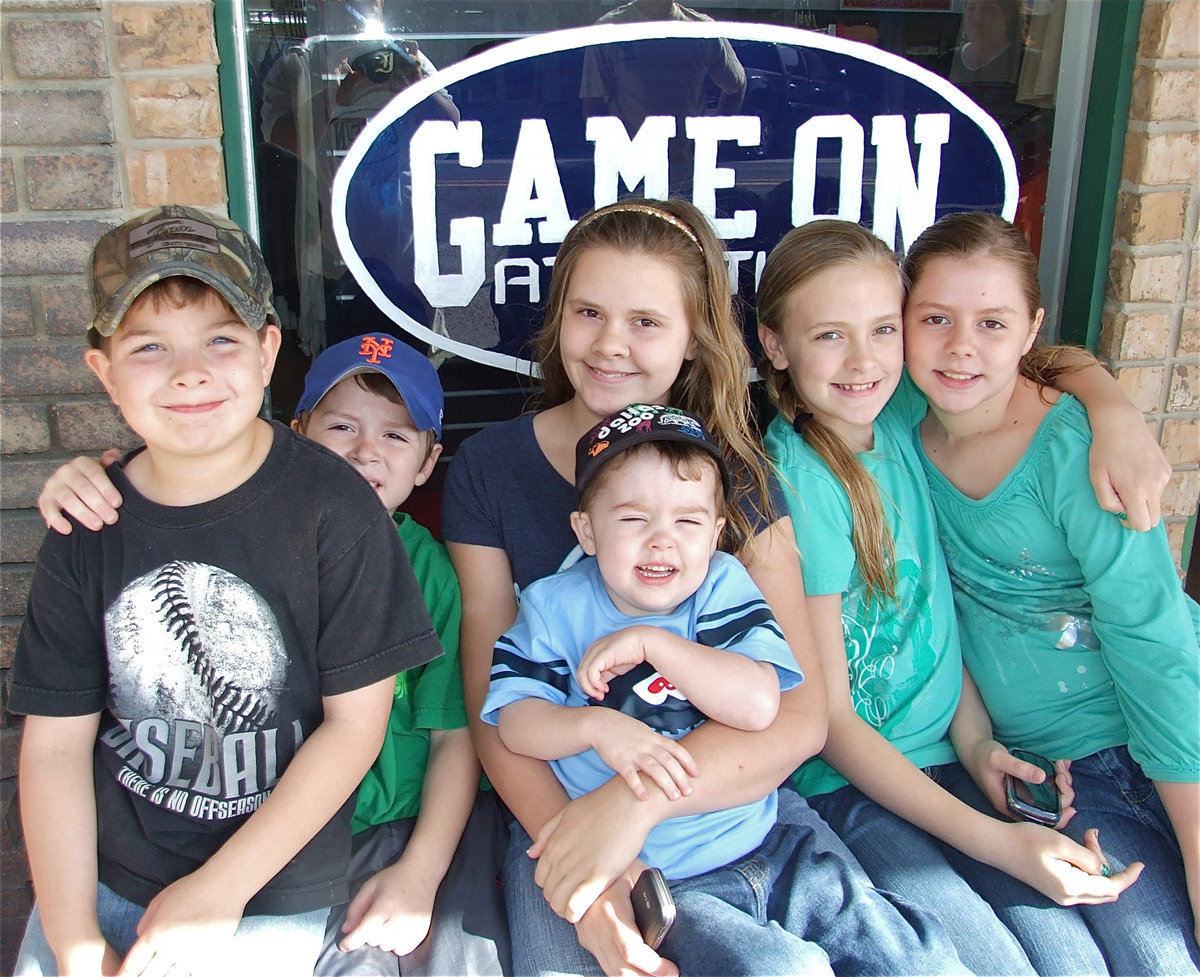 Image: Fun for all — Gage Wafer, Bryce DeBorde, Lilly Perry, Gared Wood, Annie Perry and Brooke DeBorde are pictured enjoying the grand opening celebration in front of the Game On Athletics sign.