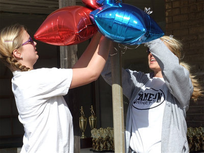 Image: The decorations — Maddy and Shelly hang balloons in front of Game On Athletics to help signal the store’s grand opening.