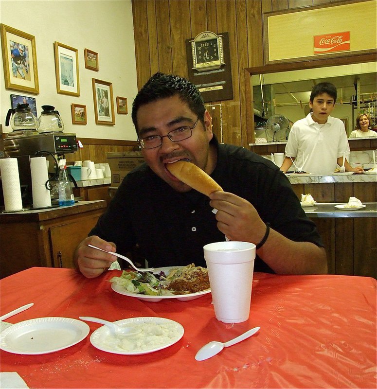 Image: Slow down, Champ! — Penny Rossa, back in the kitchen, and Juan Suaste seem concerned Gladiator Regiment Band Director, Jesus Perez, may eat all the profits during the band’s spaghetti dinner fundraiser.