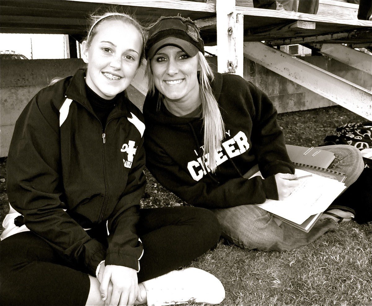Image: Quiet time — Italy Junior High Cheerleader Kelsey Nelson and Cheerleading Advisor Amanda Patrick relax at the base of the bleachers during halftime.