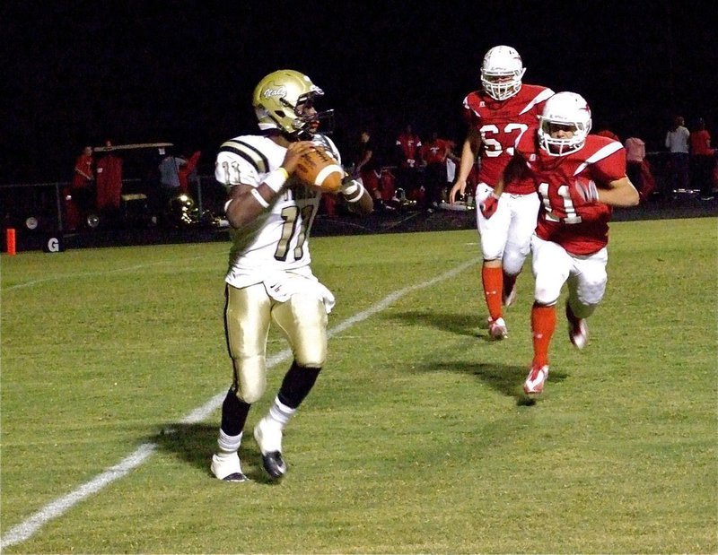 Image: Looking downfield — Jasenio Anderson(11) rolls right and searches for a receiver downfield while Axtell’s Ryan Linkous(11) and Jeremy Riser(63) put on pressure.