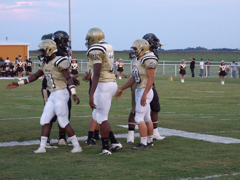 Image: Captains of the game — Jasenio Anderson (11), Larry Mayberry (77) and Ethan Simon (50) meet in the middle with the Jaguar captains.