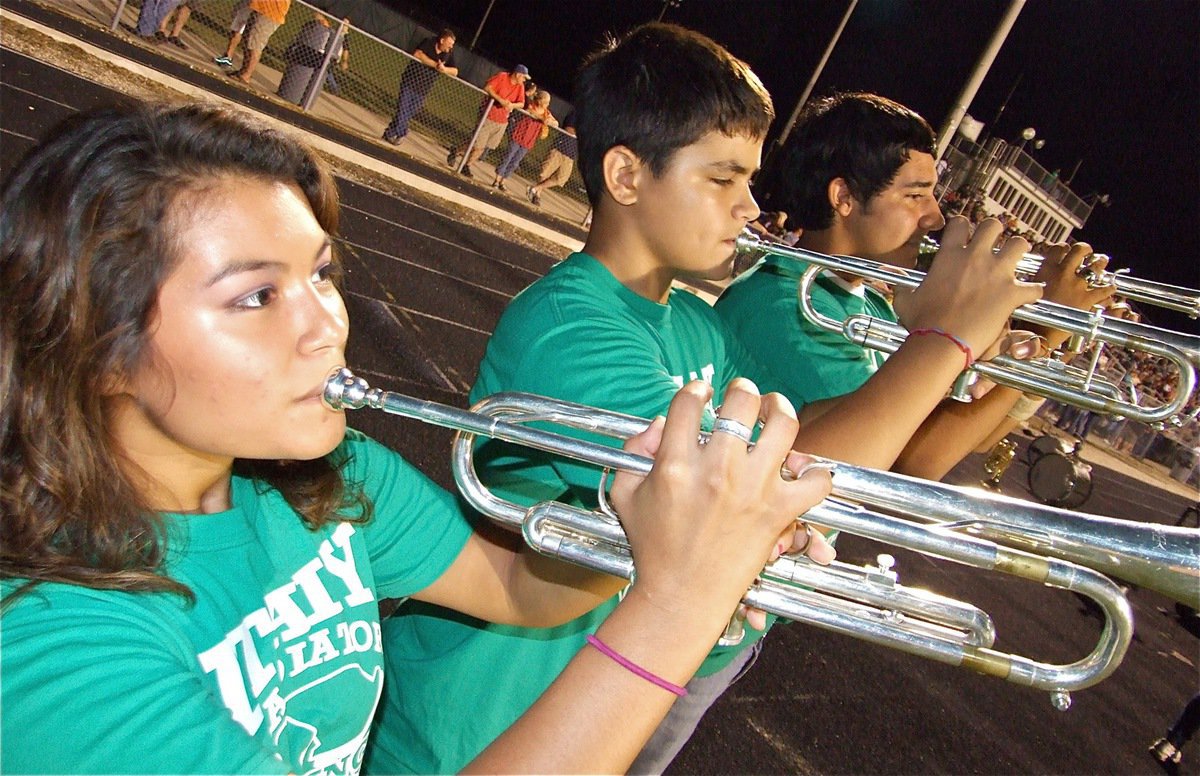 Image: Trumpeters blare away — Marisela Perez, Reid Jacinto and his cousin Michael “Taz” Martinez show Palmer’s fans how to peel green onions.