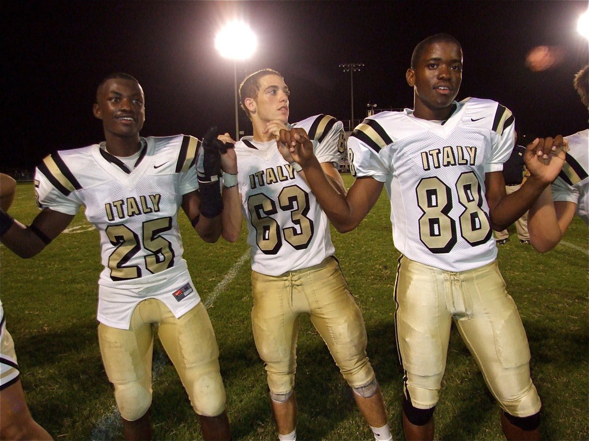 Image: School spirit — Gladiators Corrin Frazier(25), Brandon Souder(63) and Paul Harris(88) support school spirit during the Gladiator Regiments Band playing of the school song after Italy pounded the Bulldogs 27-7.
