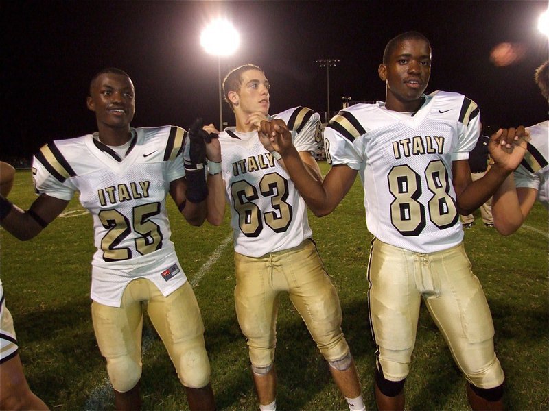 Image: School spirit — Gladiators Corrin Frazier(25), Brandon Souder(63) and Paul Harris(88) support school spirit during the Gladiator Regiments Band playing of the school song after Italy pounded the Bulldogs 27-7.