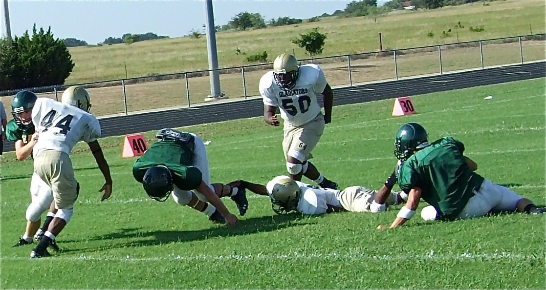 Image: Hanging on — Heath Clemons hangs on to the heel of an Eagle ground gainer as De’Andre Sephus(44) and Bobby Wilson(50) move in.