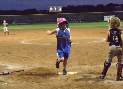 Image: Sanders stomps — Sarah Sanders stamps her cleat print on home plate as Milford’s Lil’ Dogs defeat the Ferris Scorpions 14-13 to claim the district tournament championship. Both Milford and Ferris qualify for the state tournament in Athens.