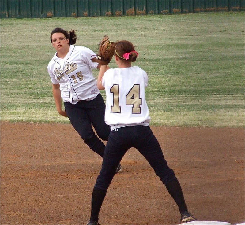 Image: Cori Jeffords(15) flips the ball to Drew Windham(14) for an out — Lady Gladiator second baseman Cori Jeffords(15) made defensive play after defensive play against Meridian in game one of the best 2-out of-3 regional quarterfinal-series on Thursday in Joshua. First baseman Drew Windham(14) caught every ball Jeffords tossed her as the two combined for 5 outs.
