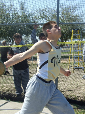 Image: Cody goes for it — 8th grader Cody Medrano unleashes a discuss throw as teammates Zain Byers and John Byers look on.