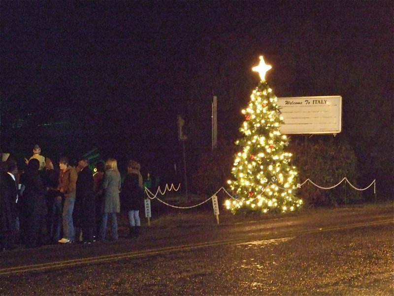 Image: The Christmas tree lights up Main Street in Italy — After the Christmas tree lights were turned on next to the marquee in downtown Italy, the congregation joined in the singing of Silent Night.