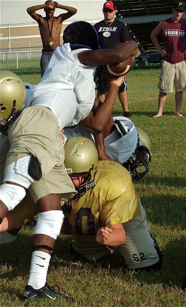 Image: Ground game — Jasenio Anderson tries to lean over a pile created by Larry Mayberry and Zain Byers(62).