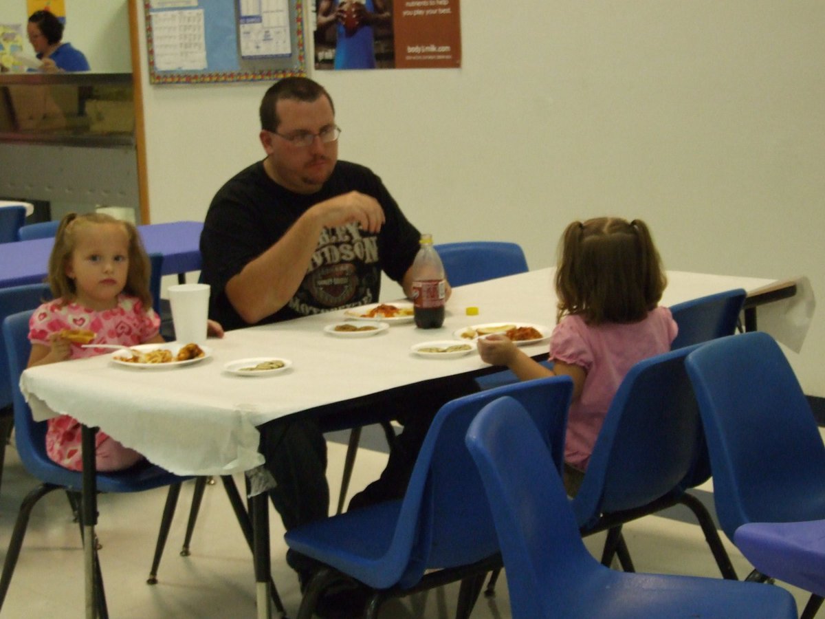 Image: Family eating together — One of the Milford families sharing a meal together and helping the cheerleaders at the same time.