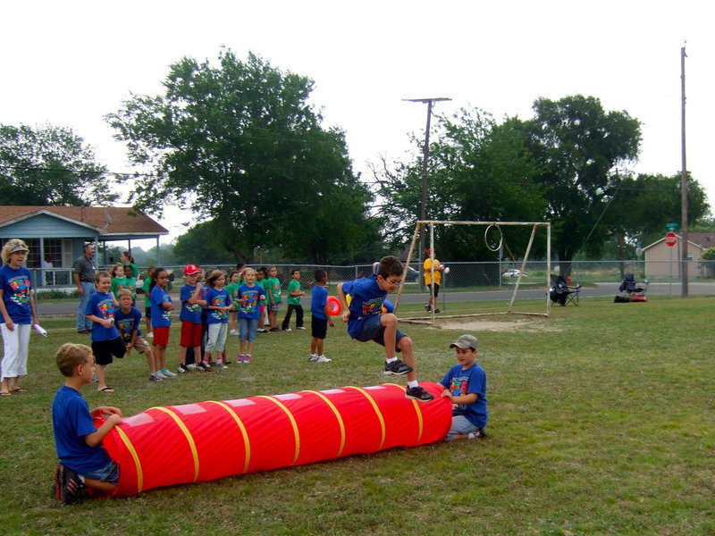 Image: This obstacle course requires the students to jump over the tube, zig zagging through the cones, jumping hurdles, kicking a ball through the cones and finally throw the football through the hoop.