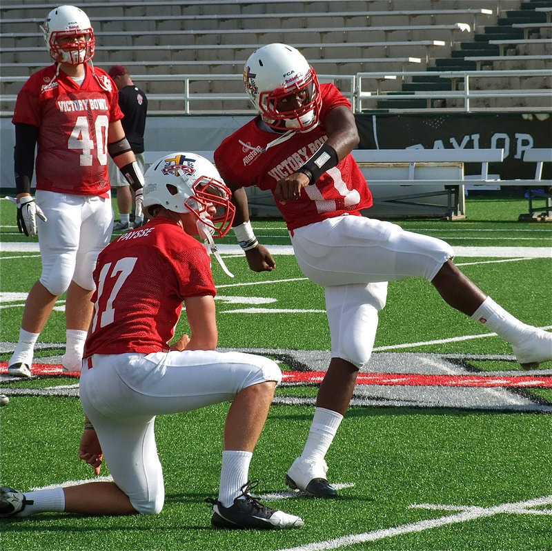 Image: Dawson’s, Nick Renfro(40), looks on as Belton’s, Jonathan Paysse(17), holds for Italy’s, Jasenio Anderson(11), as Anderson practices field goal kicks before the start of the Victory Bowl.