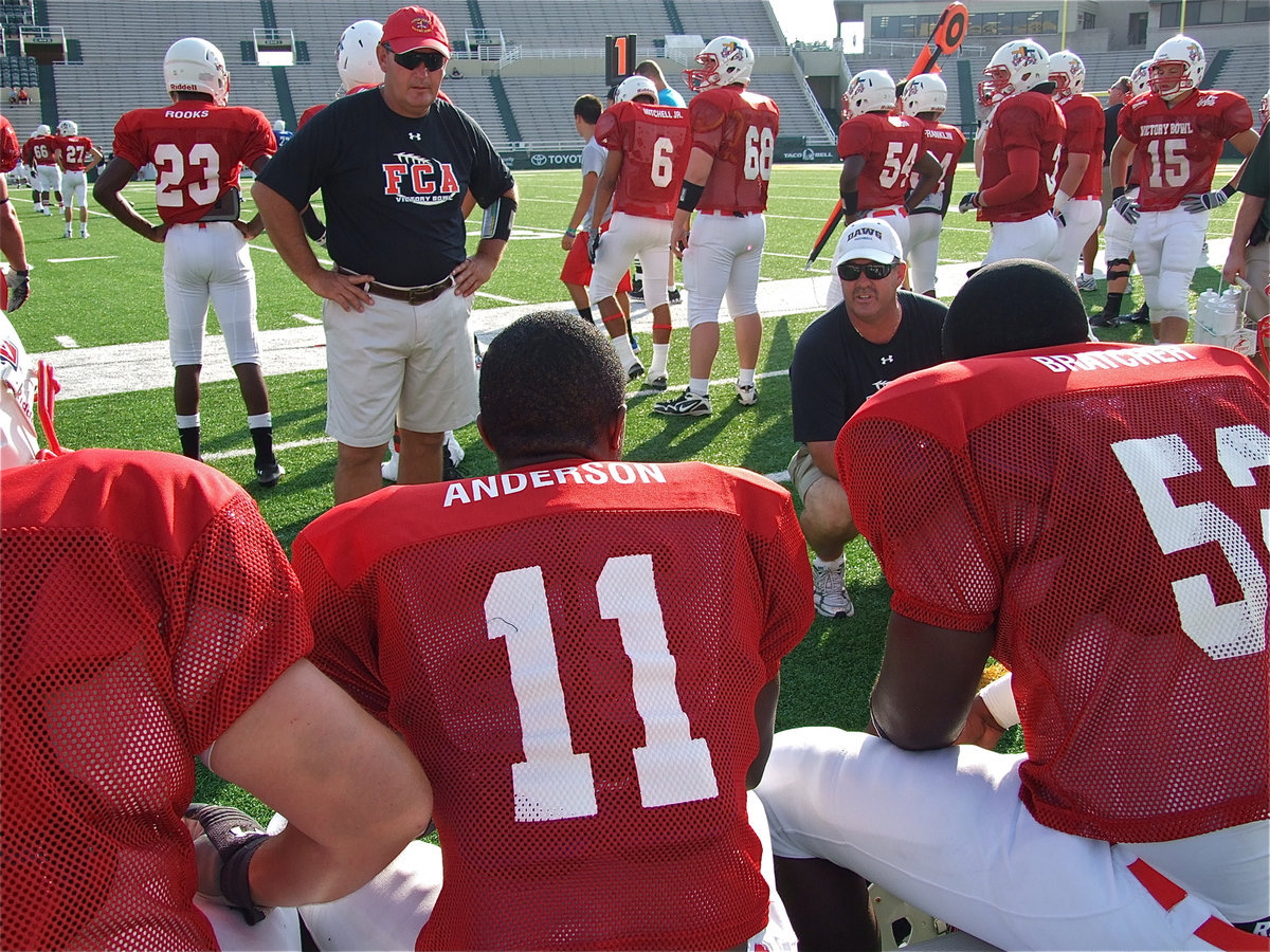 Image: Jasenio Anderson(11) and a few of his Red offensive teammates receive instructions from their coaching staff on the sideline.