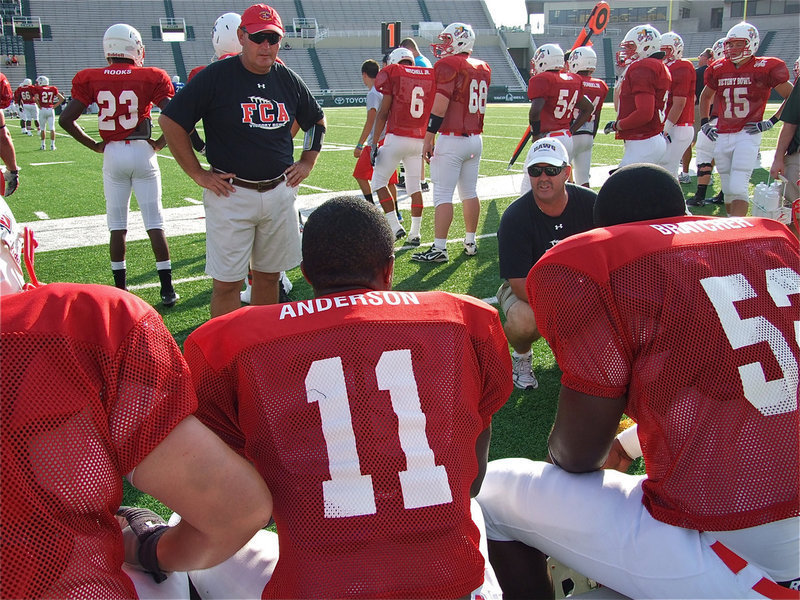 Image: Jasenio Anderson(11) and a few of his Red offensive teammates receive instructions from their coaching staff on the sideline.