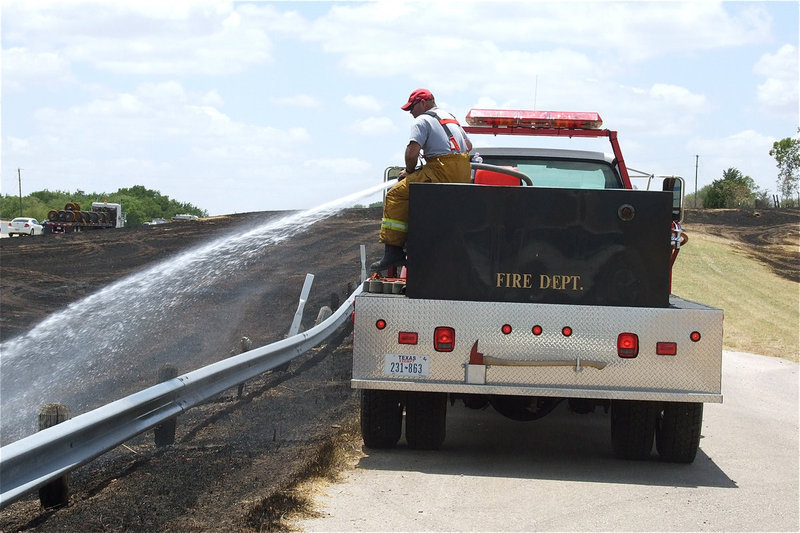 Image: Italy firefighter, Jackie Cate, hoses down the blackened landscape.