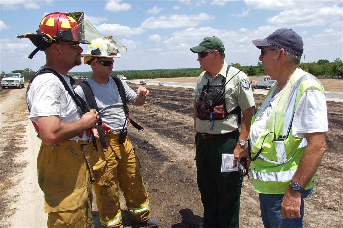 Image: Italy volunteer firefighters, Brad Chambers, Michael Chambers and their father, Donald Chambers, turn in a fire report to the Texas Forest Service documenting which fire departments responded, the number of firefighters relied on and the total number fire engines needed.