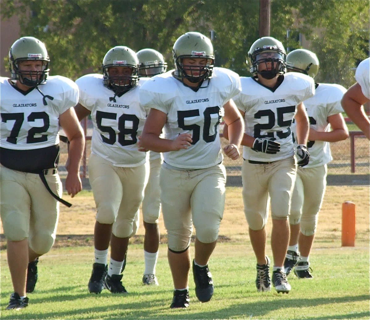 Image: Colin Newman(72), Darol Mayberry(58), Zain Byers(50) and Shad Newman(25) lead the Italy JV Gladiators onto the field to take on Maypearl.