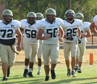 Image: Colin Newman(72), Darol Mayberry(58), Zain Byers(50) and Shad Newman(25) lead the Italy JV Gladiators onto the field to take on Maypearl.