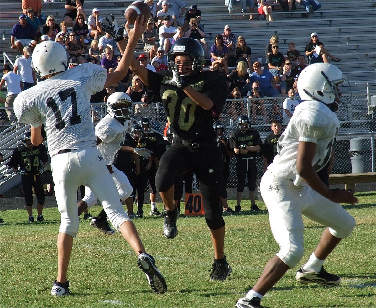 Image: Italy’s Ryan Connor(17) completes a pass to teammate Chasston King(20) with Bulldog’s paw in his line of sight.