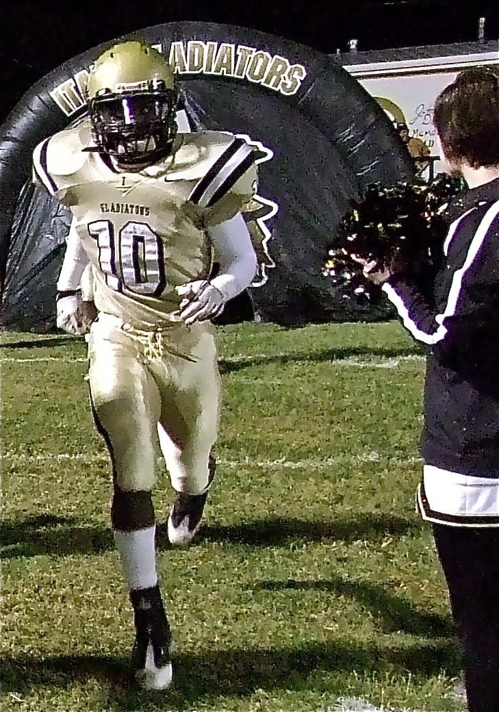 Image: IHS cheerleader Meagan Hooker cheers on Ryheem Walker and the Gladiators as they exit the tunnel to take on the Axtel Longhorns.