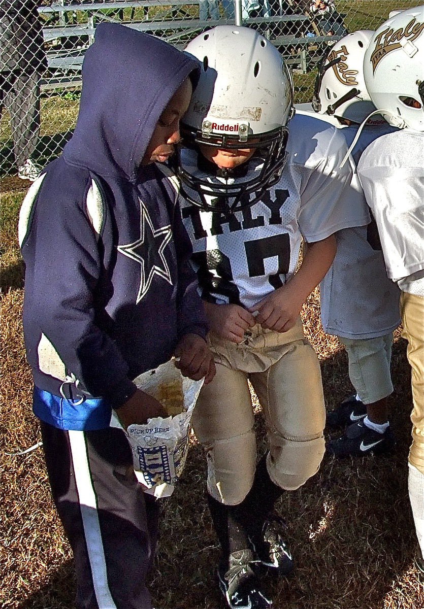 Image: IYAA B-Team star, Joe Jackson, offers some victory popcorn to Gabe Martinez(67) after the C-Team 25-7 win over Dawson.